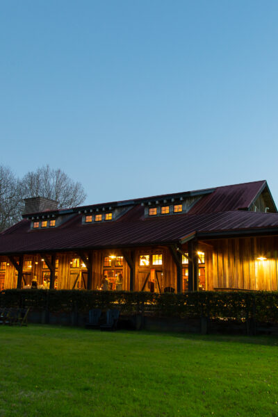 Rustic wooden house warmly lit at dusk with a clear sky.