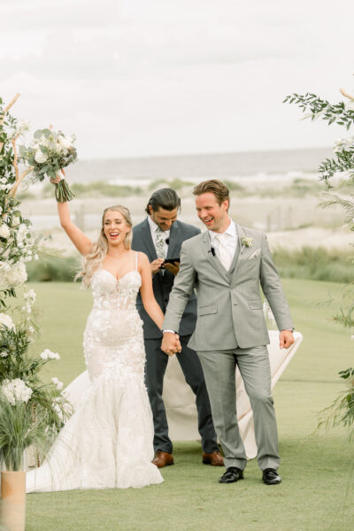 Newlyweds joyfully walk down the aisle after their outdoor wedding ceremony.