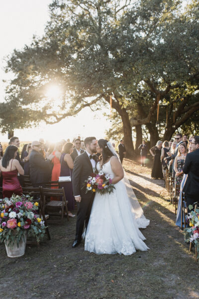 Bride and groom share a kiss at an outdoor wedding ceremony.
