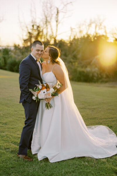 Bride and groom sharing a tender moment outdoors at sunset.