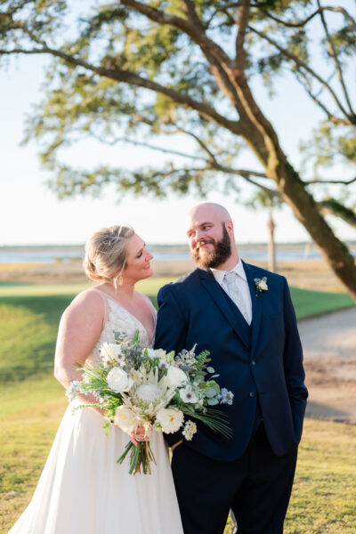 Bride and groom share a joyful moment outdoors on their wedding day.