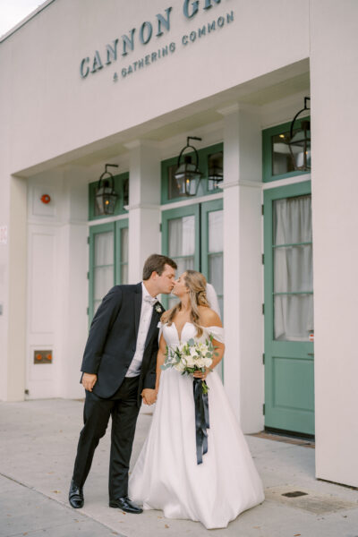 A bride and groom kiss in front of green doors during their wedding.