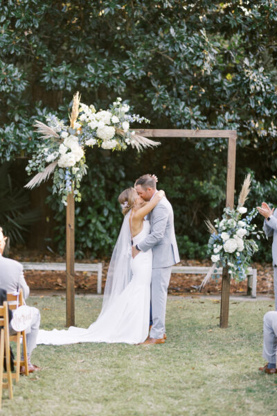 A couple shares a kiss during an outdoor wedding ceremony.
