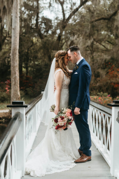 Bride and groom sharing a tender moment on a white bridge.