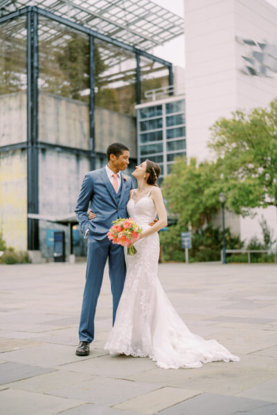 Bride and groom sharing a tender moment outdoors in wedding attire.