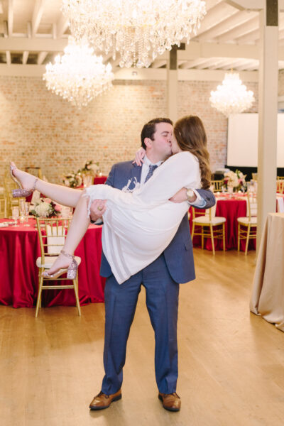 Groom lovingly carries bride at their wedding reception.