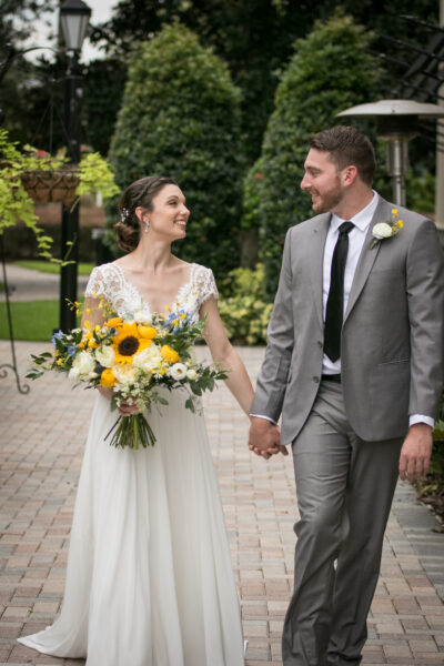 Bride and groom holding hands and smiling outdoors.