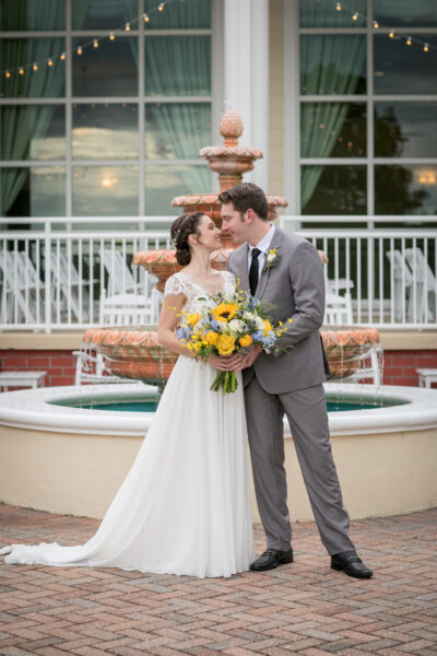 Bride and groom sharing a kiss in front of a fountain on their wedding day.