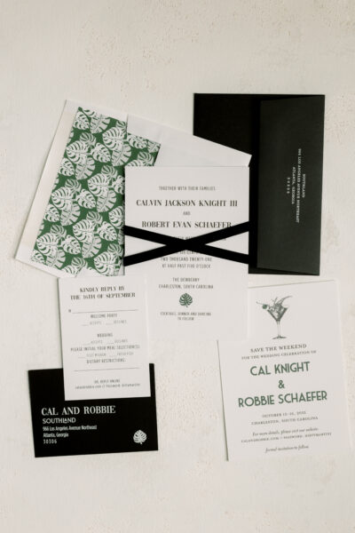 Elegant black and white wedding invitations with floral accents and ribbons.