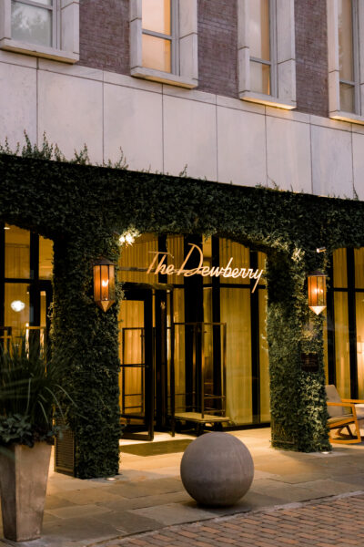 Elegant entrance of a restaurant adorned with greenery and warm lighting.