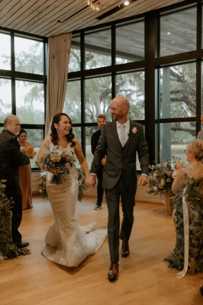 Newlywed couple joyfully walking down the aisle surrounded by guests.