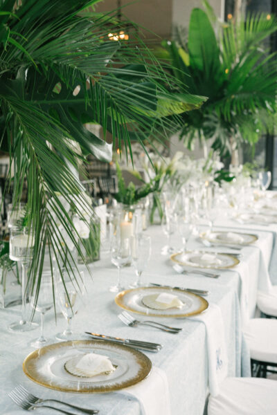 Elegant dining table set with crystal glassware and tropical greenery.