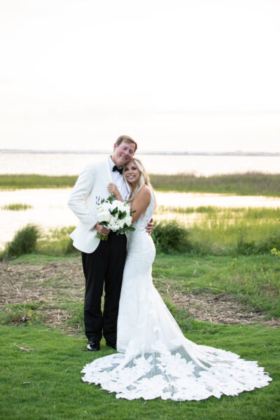 Newlywed couple embraces outdoors near a lake, radiating happiness.