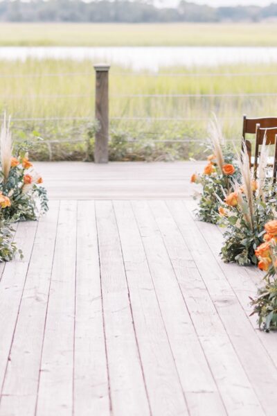 Rustic wooden aisle decorated with floral arrangements for an outdoor wedding.