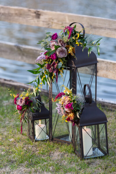 Decorative black lanterns adorned with vibrant floral arrangements outdoors.