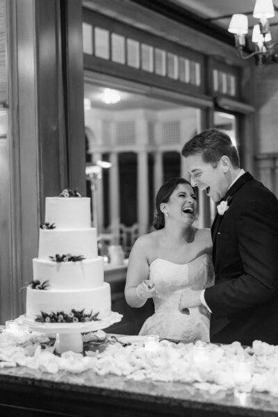 Happy couple laughing together at their wedding cake.