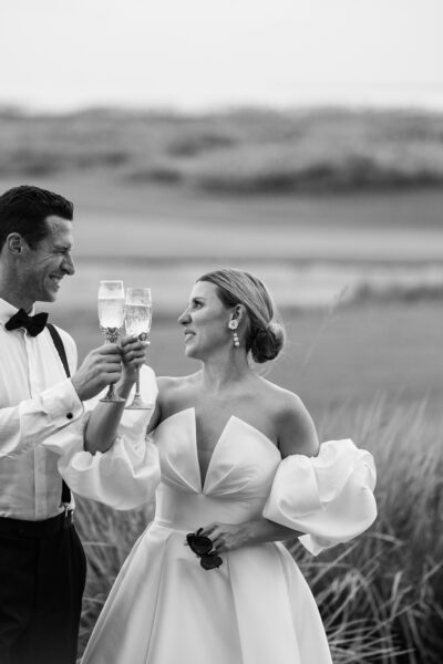 A couple shares a joyful moment outdoors in elegant attire.