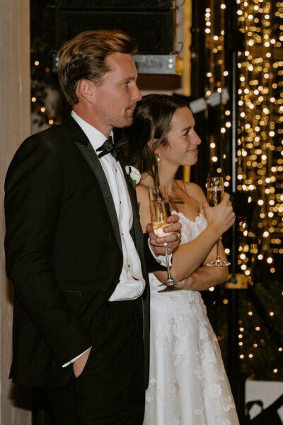 Elegant couple enjoying a formal event with sparkling lights in the background.
