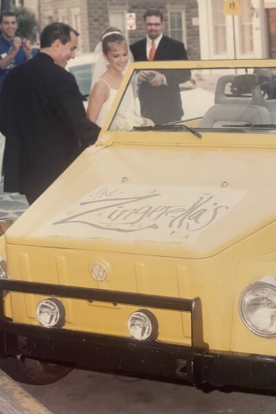 Yellow classic convertible car with cursive text on the hood.
