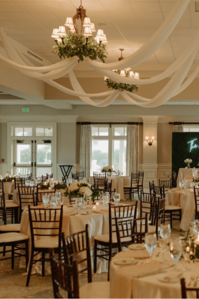 Elegant wedding reception setup with chandeliers and draped fabric.