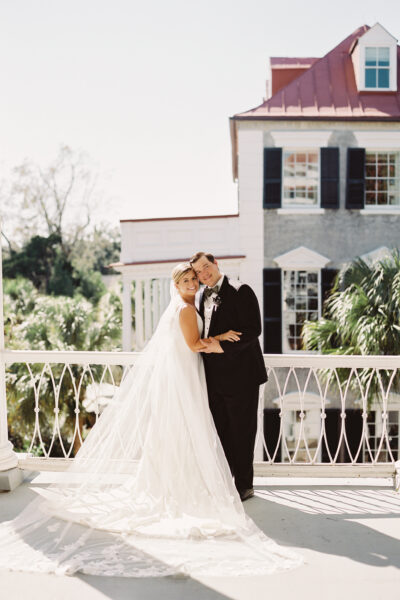 Bride and groom embracing on a balcony during their wedding day.