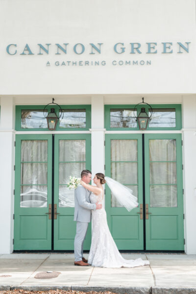 Bride and groom embrace in front of green doors at Cannon Green venue.