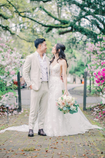 Bride and groom sharing a romantic moment surrounded by blooming flowers.