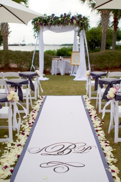 Elegant outdoor wedding aisle decorated with white and purple flowers.