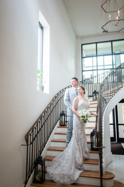 Bride and groom posing on a staircase in a bright, modern venue.