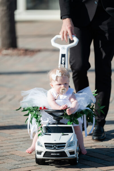 A baby dressed as an angel sitting in a decorated stroller.