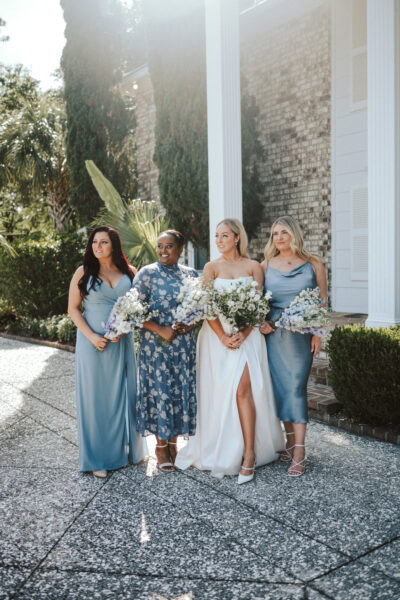 Bride with bridesmaids in blue dresses outdoors.