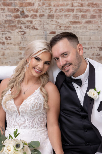A smiling bride and groom posing together at their wedding.