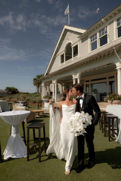 Bride and groom share a kiss outside a charming venue on their wedding day.
