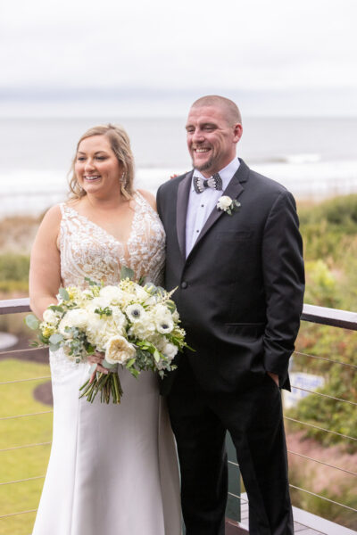 Bride and groom smiling outdoors on their wedding day.