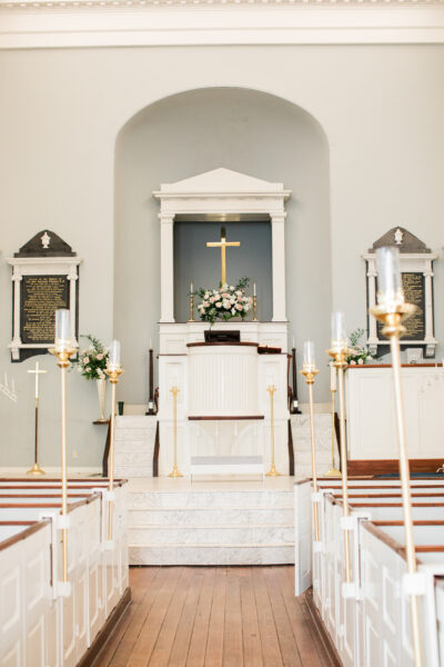 A beautifully decorated church altar with lit candles and floral arrangements.