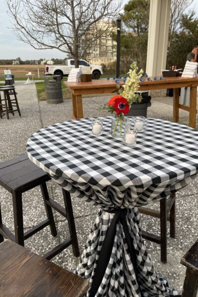 Outdoor table with black and white checkered cloth and flower centerpiece.