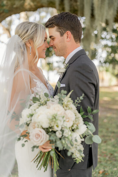 Bride and groom sharing a tender moment outdoors on their wedding day.
