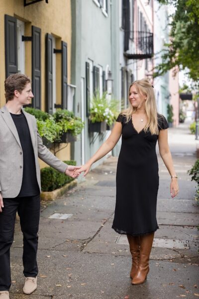 Couple holding hands and walking on a sidewalk in a charming neighborhood.
