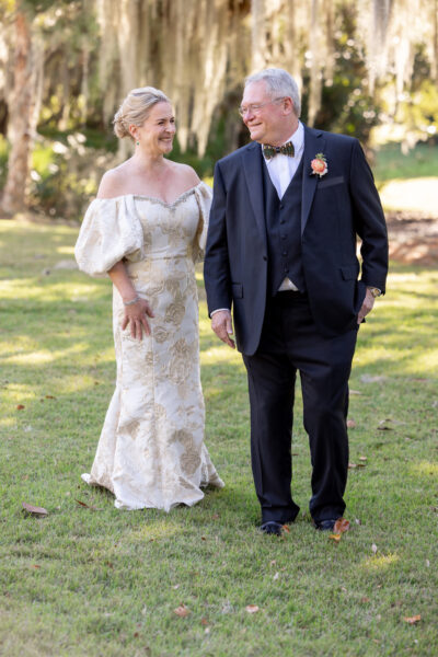 A bride and groom walking together outdoors, smiling.