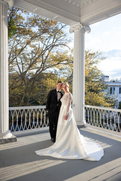 Bride and groom share a kiss on a scenic balcony during sunset.