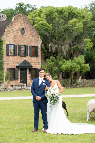 Newlywed couple posing happily outside a rustic brick building during their wedding.