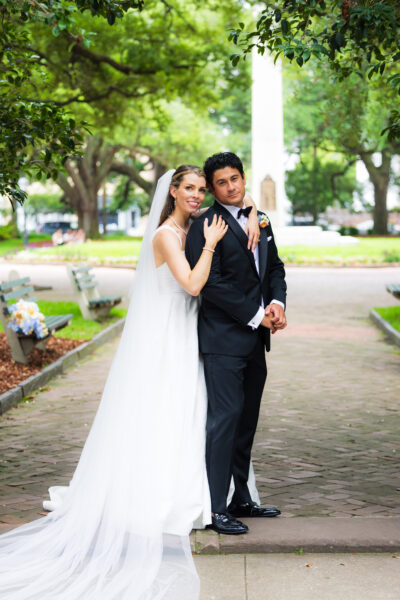 Bride and groom posing outdoors in wedding attire.