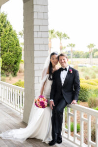 Bride and groom posing happily on a porch after their wedding.
