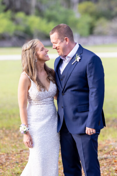 Bride and groom sharing a joyful moment outdoors on their wedding day.