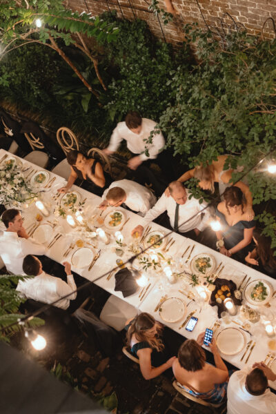 Outdoor evening dinner party with string lights and long table setup.