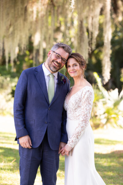 Smiling couple posing outdoors in formal attire.